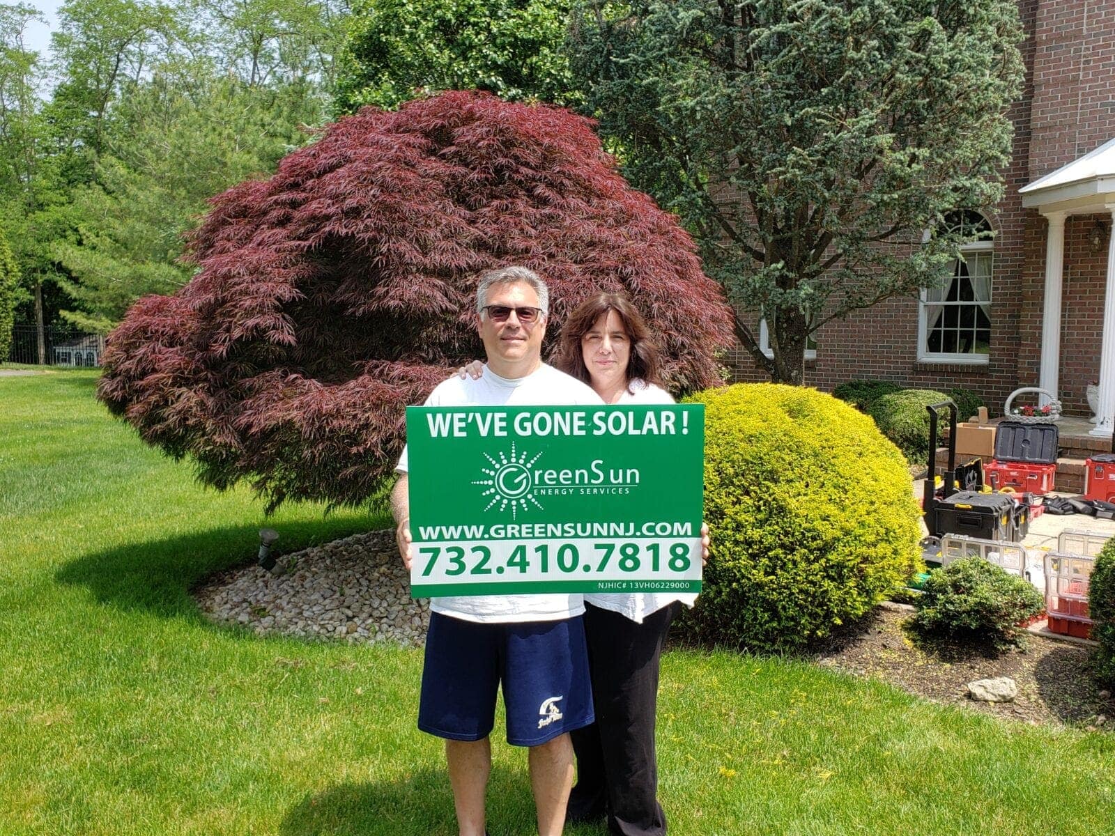 Happy solar customers in Monmouth County, NJ holding a Green Sun Energy Services lawn sign after going solar